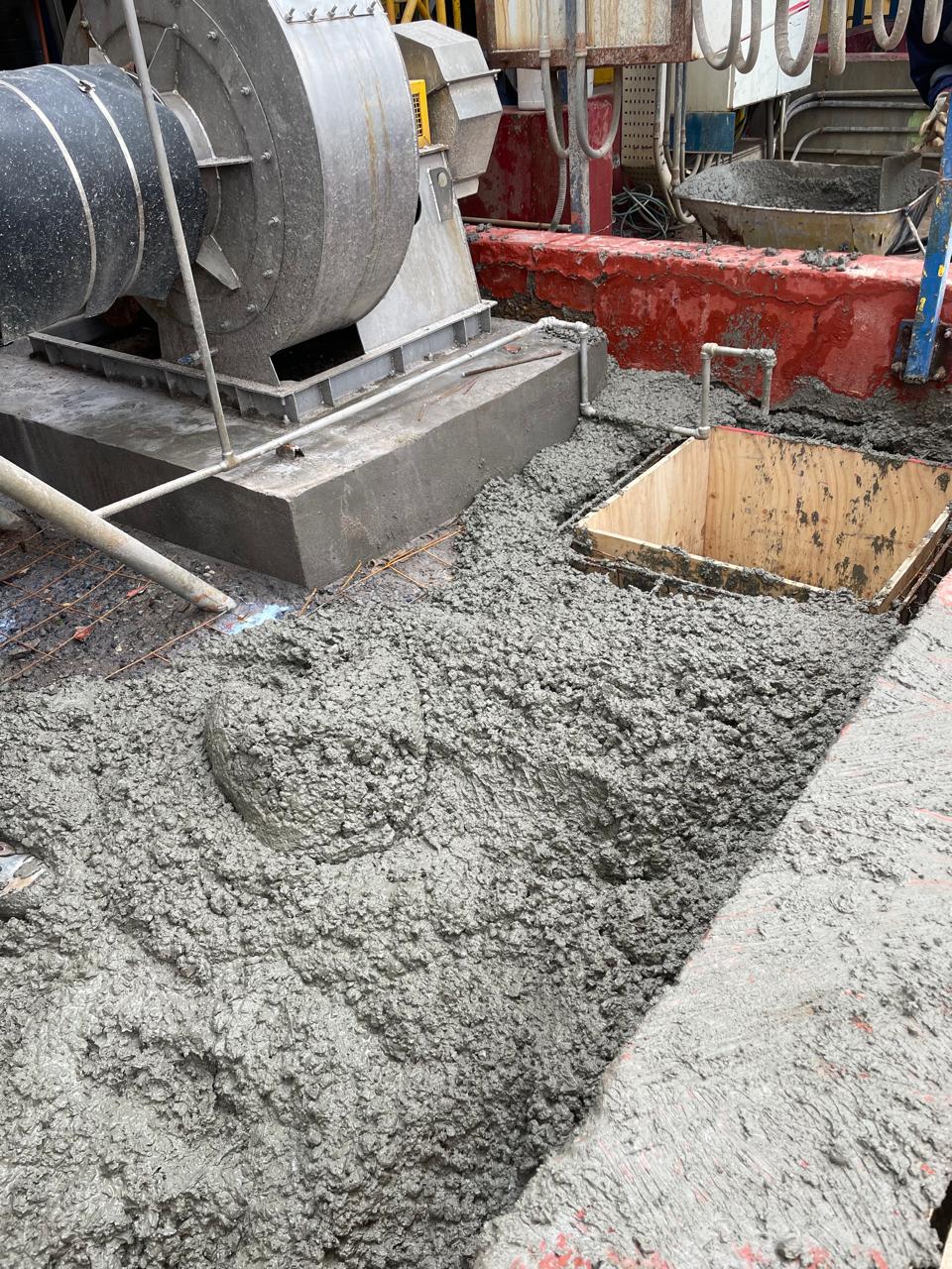 Aplicación de concreto fresco para la reconstrucción de bases de equipos y pretiles de contención en un entorno industrial.