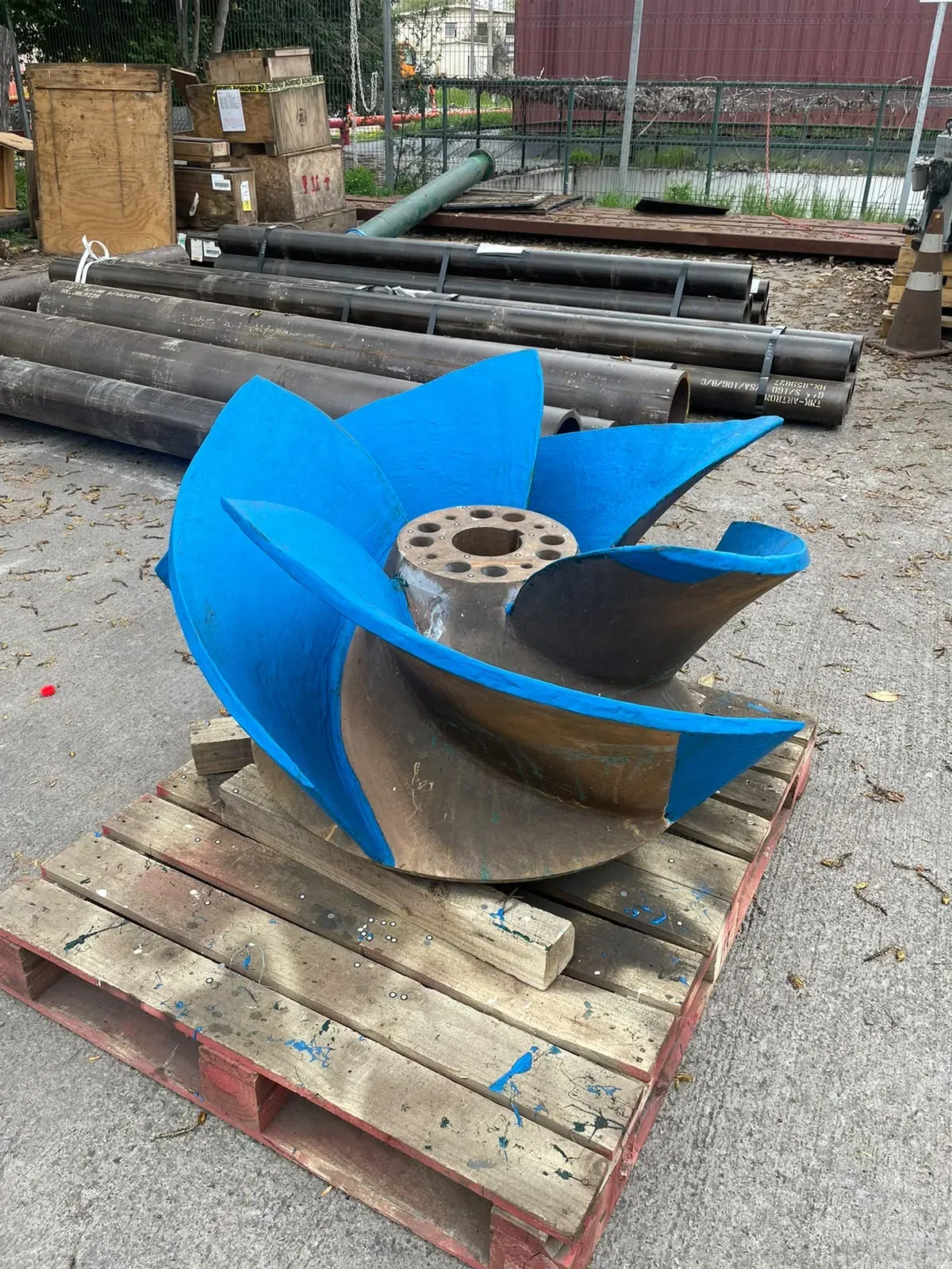 Rodete de bomba industrial sobre pallet de madera, con recubrimiento polimérico azul brillante aplicado parcialmente en sus álabes para protección contra la erosión y cavitación.