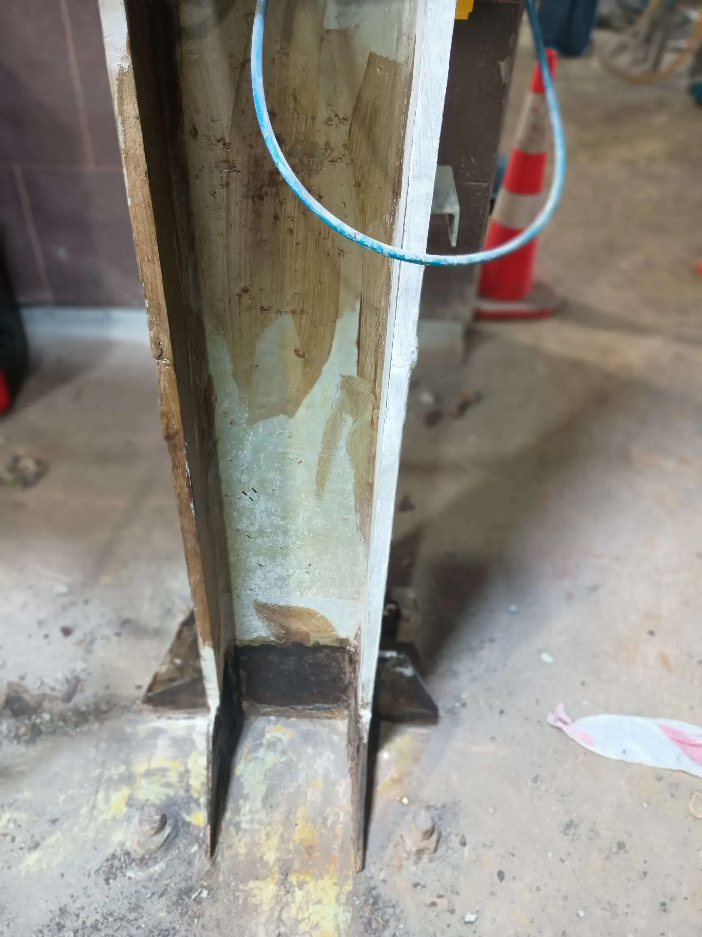 Columna de acero estructural con preparación de superficie y recubrimiento polimérico aplicado en el alma y alas, anclada a piso industrial.