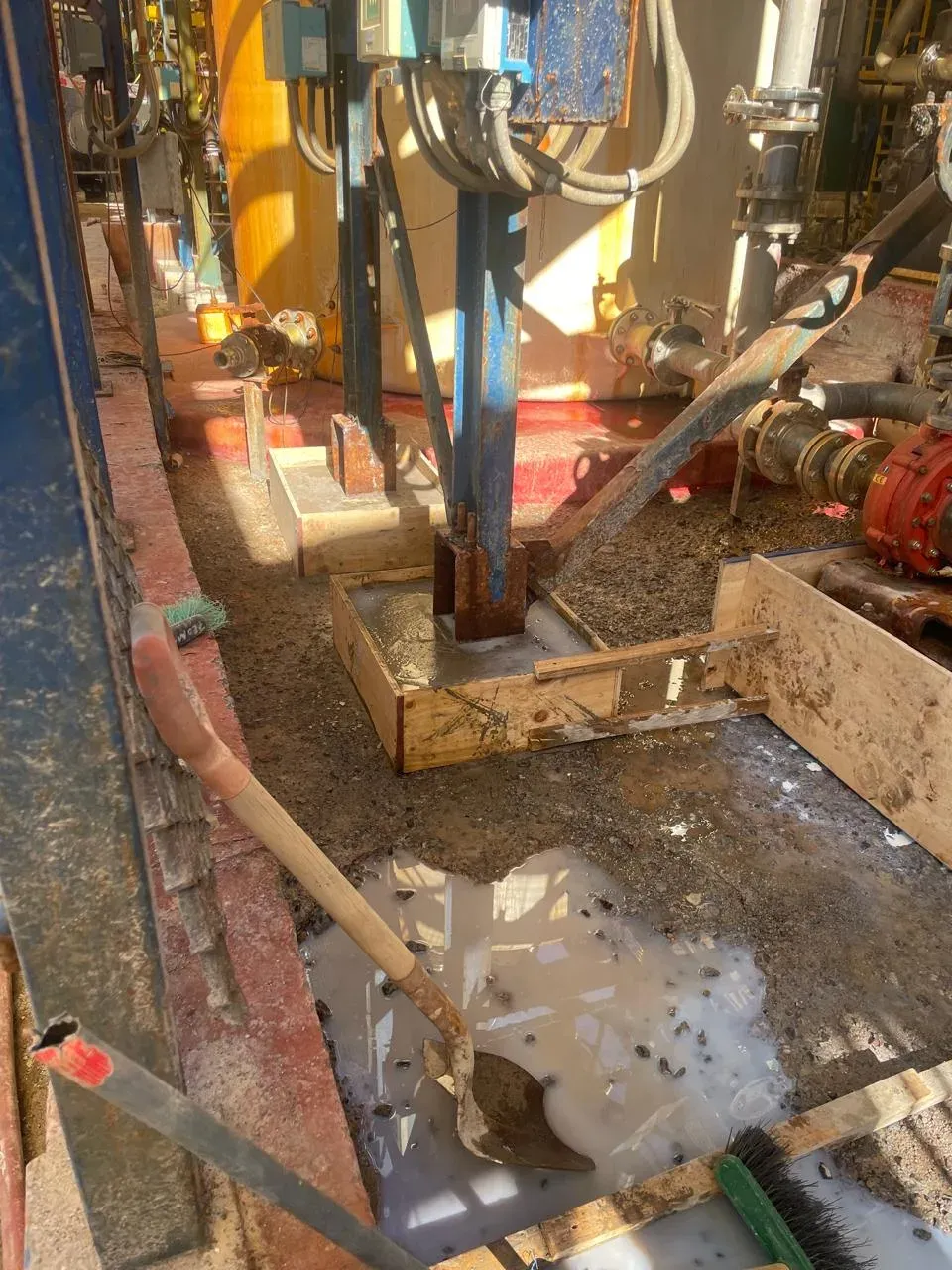 Bases de soporte estructural de acero en reparación mediante vaciado de mortero polimérico en moldajes de madera, dentro de una planta industrial.